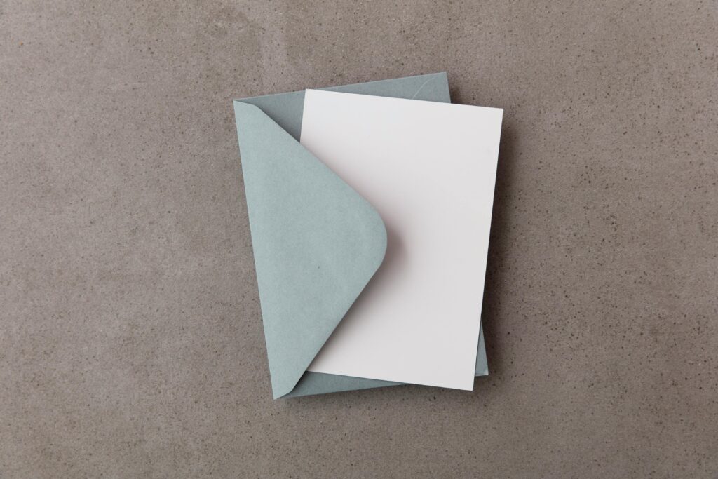 Flat lay of a blue envelope with an open blank card on concrete texture.